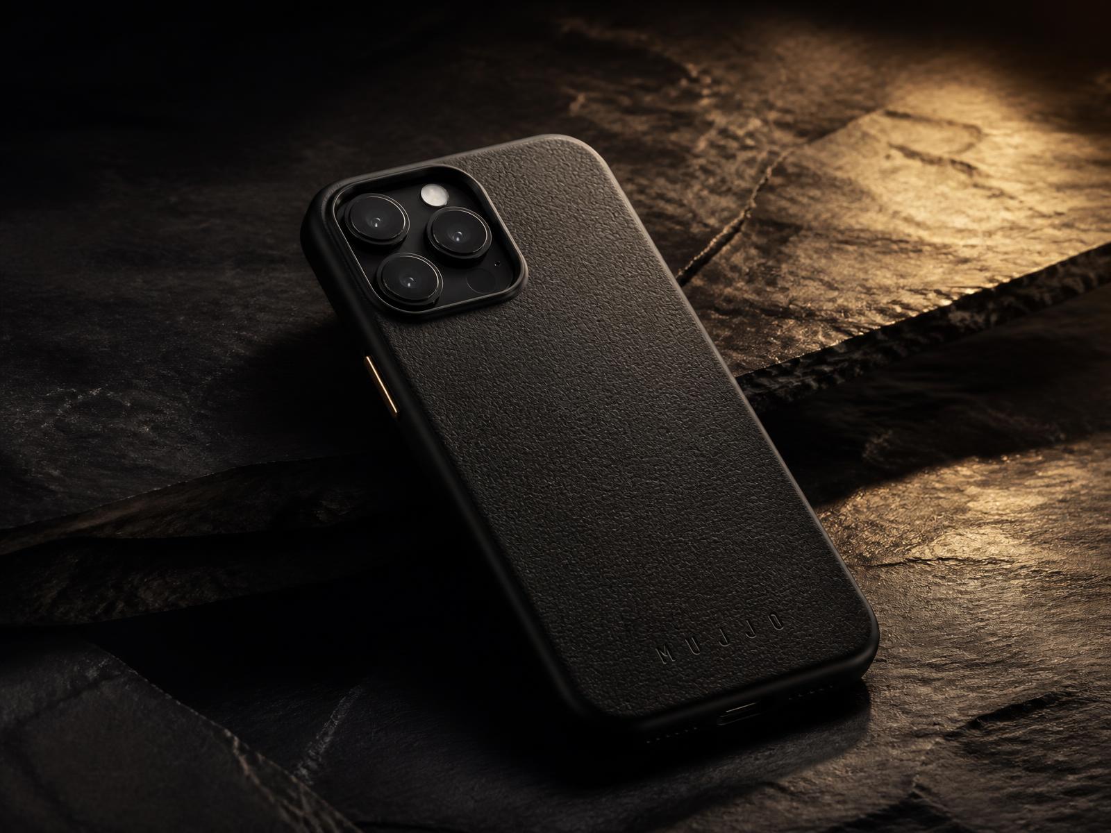 Premium black phone case on dark stone with warm gold light